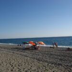 Spiaggia della Riviera Ligure con sabbia dorata e mare cristallino, simbolo di pulizia e bellezza naturale.