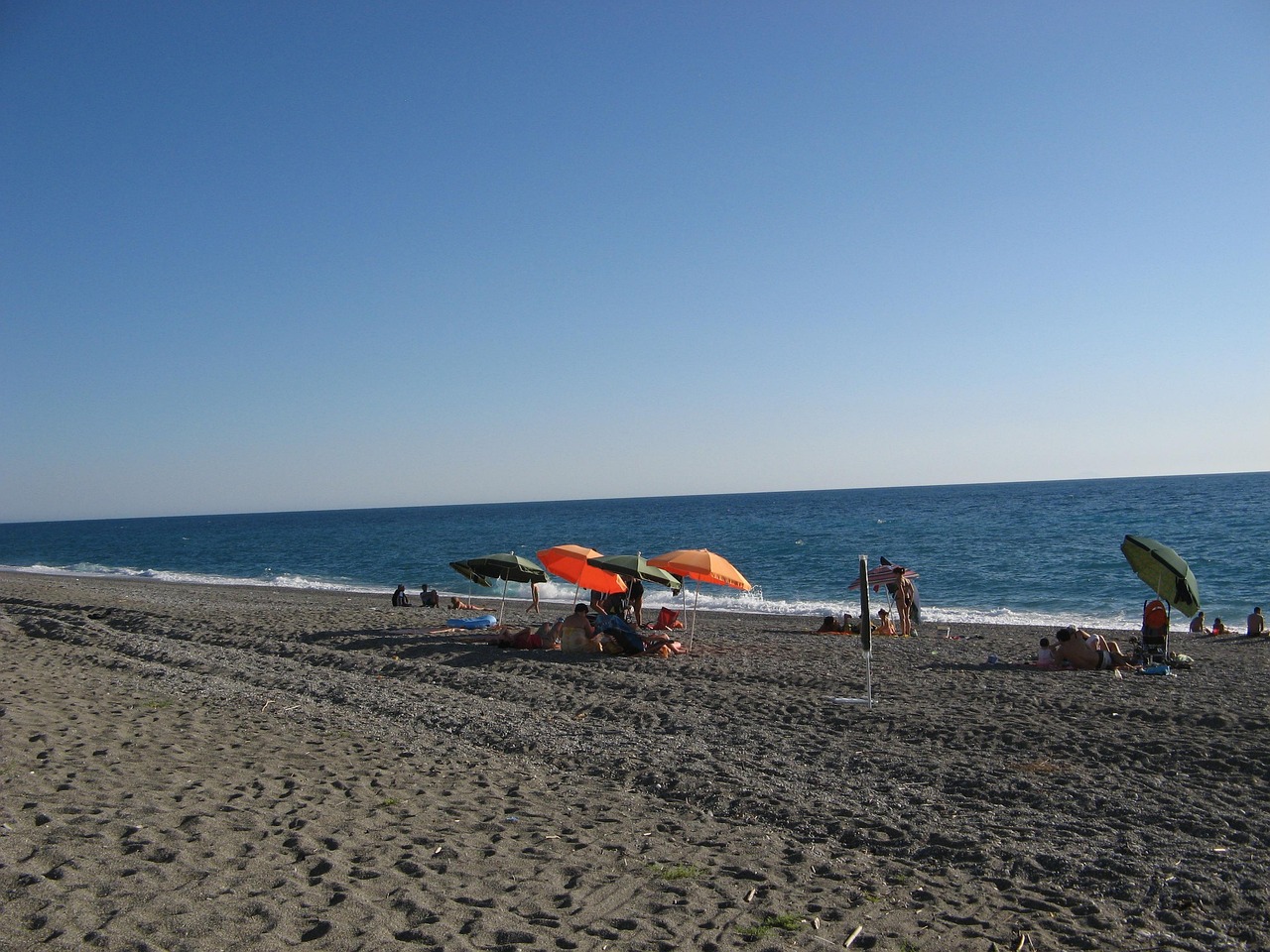 Spiaggia della Riviera Ligure con sabbia dorata e mare cristallino, simbolo di pulizia e bellezza naturale.