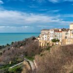 Due innamorati in un romantico paesaggio primaverile italiano, circondati da fiori e natura.