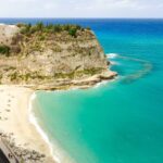Spiaggia nascosta in Italia, sabbia dorata e acque cristalline, ideale per una fuga estiva.