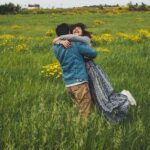 Coppia felice in un paesaggio primaverile romantico, simbolo di viaggi da sogno sotto i 1.000 euro.