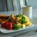 Colazione salata con avocado, pomodoro e pane integrale su un piatto colorato.