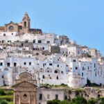 Borgo pugliese con architettura tipica, stradine acciottolate e atmosfera da villaggio europeo.