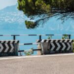 Percorso ciclabile panoramico lungo la costa italiana, con vista mare e ciclisti in movimento.