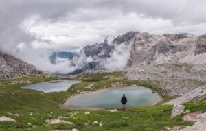 Panorama delle Dolomiti in primavera con fiori colorati e cime innevate.