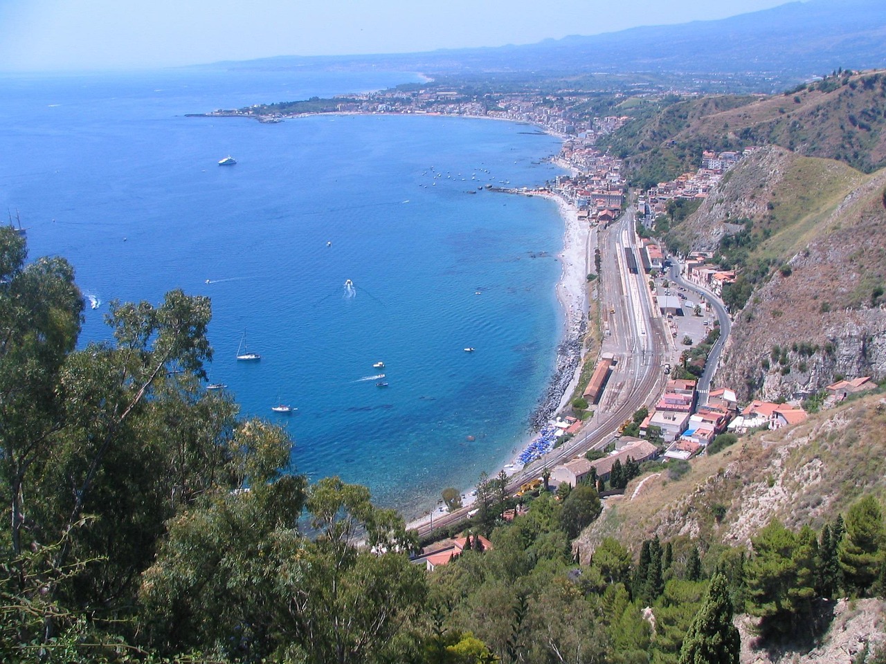 Panorama mozzafiato di una spiaggia siciliana con mare cristallino e scogliere.