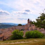 Paesaggio sereno dell'Umbria, con colline verdi e cielo azzurro, rappresentante la tranquillità del paese.