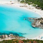Spiaggia incontaminata della Sardegna, accessibile solo a piedi, con acque cristalline e sabbia bianca.
