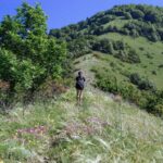 Escursionista su un sentiero panoramico in Italia, circondato da paesaggi mozzafiato e natura incontaminata.