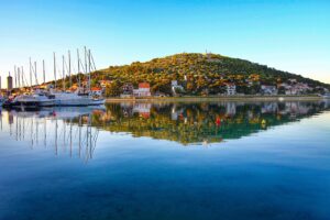 Cittadina costiera croata con mare cristallino e architettura storica.